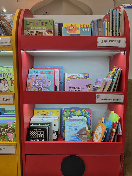 Red bookshelf of interactive books for newborns and toddlers at Brain Chapters